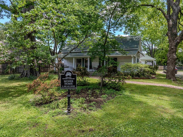 view of property hidden behind natural elements featuring a shingled roof