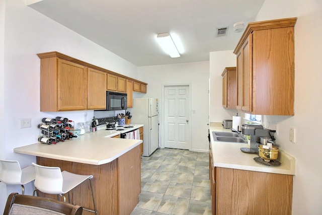 1079 River Isle Dr, Memphis, TN 38103 - kitchen featuring black microwave, electric range oven, light countertops, freestanding refrigerator, and a peninsula
