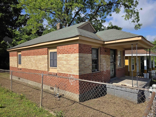 view of side of property with crawl space, a porch, fence, brick siding, and a chimney