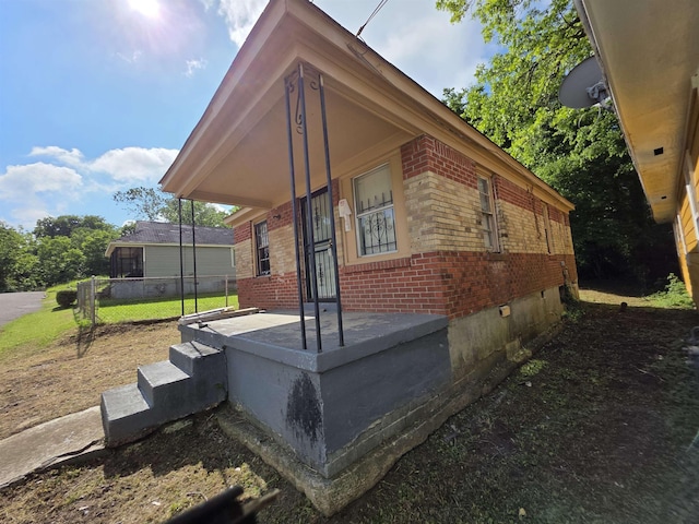 view of side of home with brick siding and fence