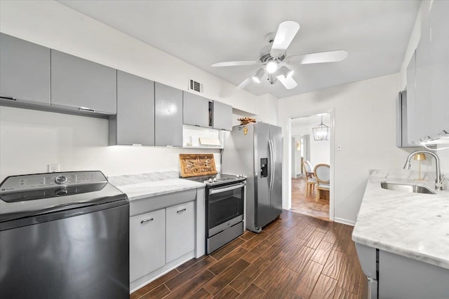 kitchen featuring washer / dryer, stainless steel appliances, a sink, gray cabinets, and ceiling fan