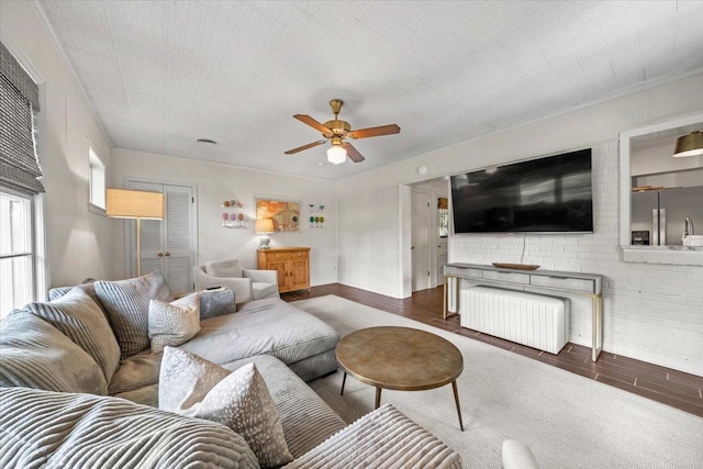 living area with a ceiling fan, wood finished floors, and crown molding