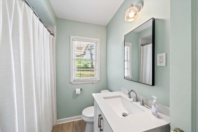 bathroom featuring toilet, vanity, wood finished floors, and baseboards