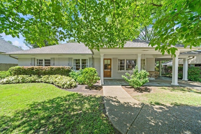 ranch-style house featuring brick siding, a porch, a front yard, and an attached carport