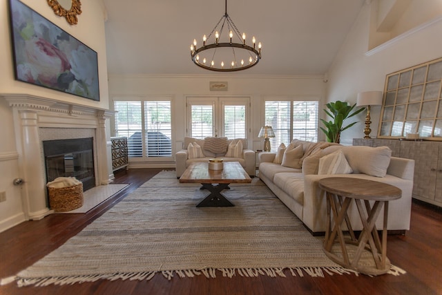 living area featuring a chandelier, a glass covered fireplace, high vaulted ceiling, wood finished floors, and crown molding
