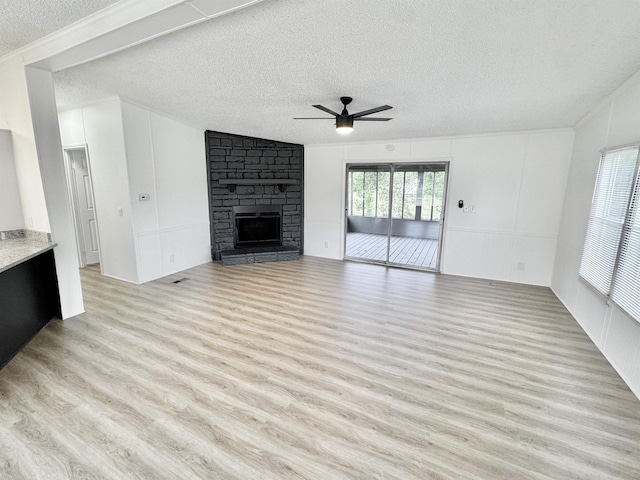 841 Simmons Rd, Munford, TN 38023 - unfurnished living room featuring a textured ceiling, ceiling fan, light wood-type flooring, a stone fireplace, and ornamental molding