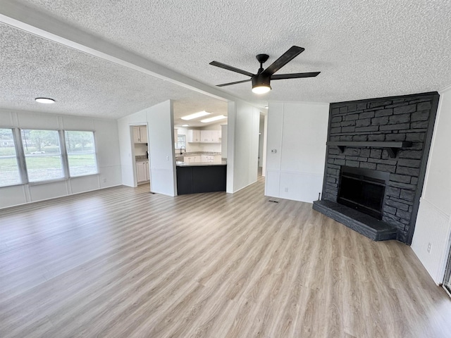 841 Simmons Rd, Munford, TN 38023 - unfurnished living room featuring a textured ceiling, light wood-style flooring, a ceiling fan, and a fireplace