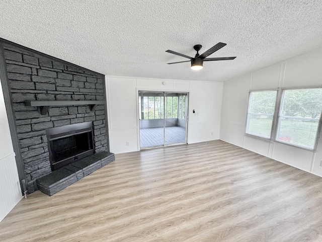 841 Simmons Rd, Munford, TN 38023 - unfurnished living room with vaulted ceiling, a textured ceiling, wood finished floors, ceiling fan, and a fireplace