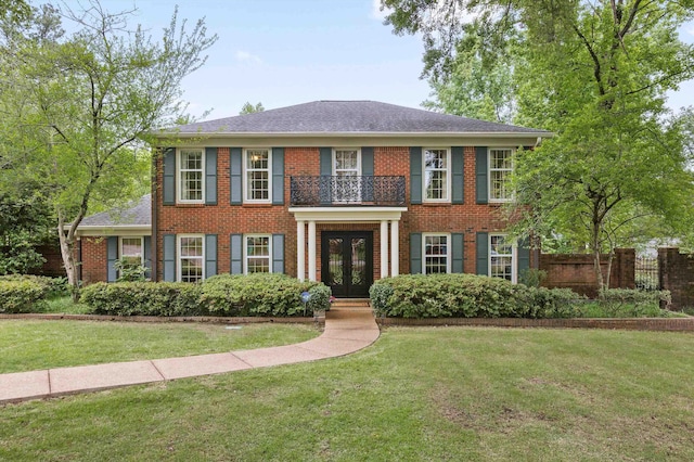 colonial home featuring french doors, a balcony, and brick siding