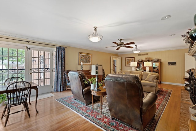 living area with ceiling fan, light wood-style flooring, ornamental molding, and baseboards