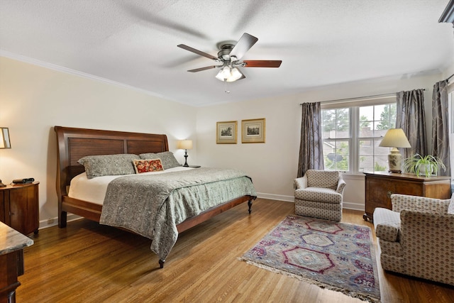 bedroom with wood finished floors, baseboards, ornamental molding, a ceiling fan, and a textured ceiling