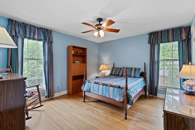 bedroom featuring multiple windows, light wood-type flooring, baseboards, and a ceiling fan