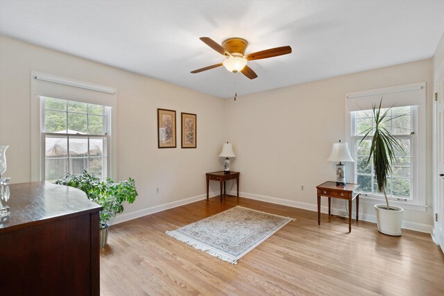 living area with a ceiling fan, light wood-style floors, and baseboards