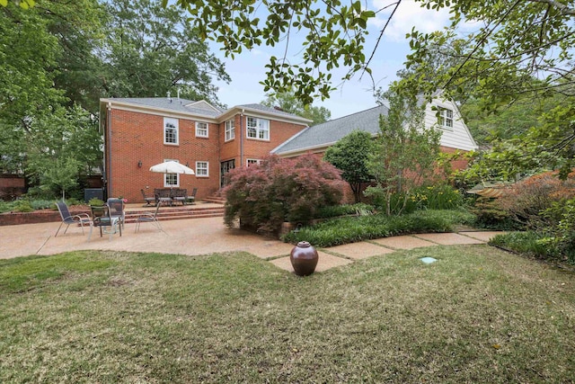 rear view of property with brick siding, a patio, and a lawn