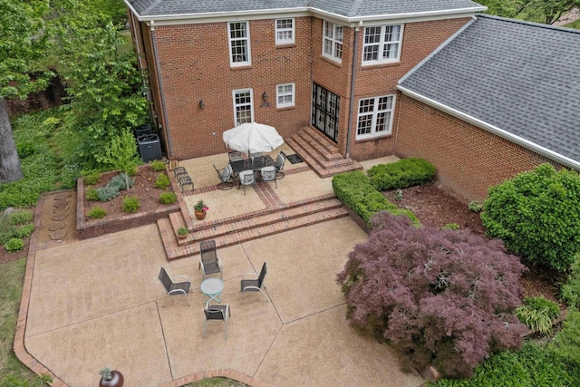 back of property featuring a patio, roof with shingles, brick siding, and central air condition unit
