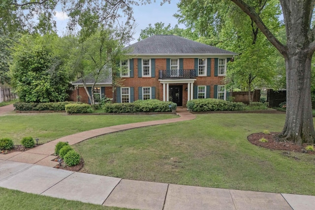 georgian-style home featuring brick siding and a balcony