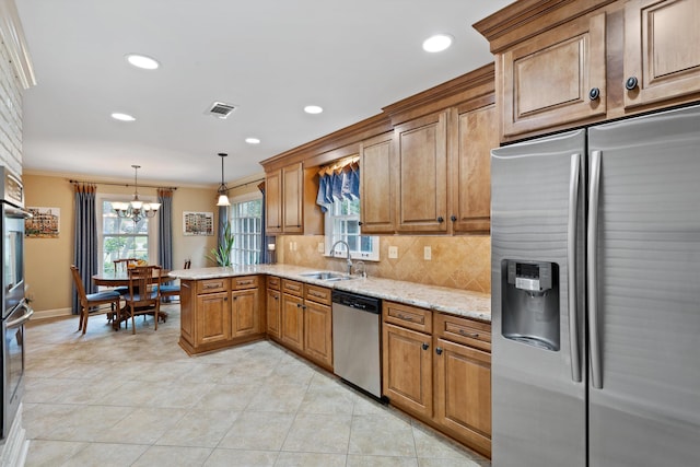 kitchen featuring appliances with stainless steel finishes, ornamental molding, a chandelier, tasteful backsplash, and light stone counters