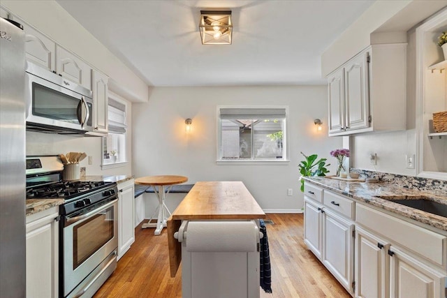 3686 Charleswood Ave, Memphis, TN 38122 - kitchen featuring stainless steel appliances, light stone counters, light wood finished floors, and baseboards