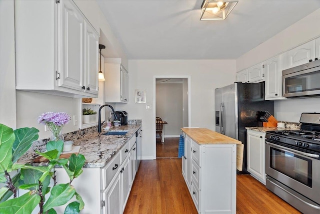 3686 Charleswood Ave, Memphis, TN 38122 - kitchen with stainless steel appliances, a sink, white cabinetry, wood finished floors, and light stone countertops