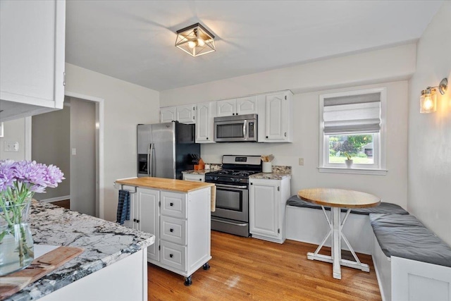 3686 Charleswood Ave, Memphis, TN 38122 - kitchen featuring appliances with stainless steel finishes, white cabinetry, wood counters, and light wood-style floors