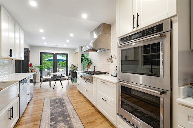 1366 Kirby Rd, Memphis, TN 38120 - kitchen featuring stainless steel appliances, wall chimney exhaust hood, tasteful backsplash, white cabinetry, and recessed lighting