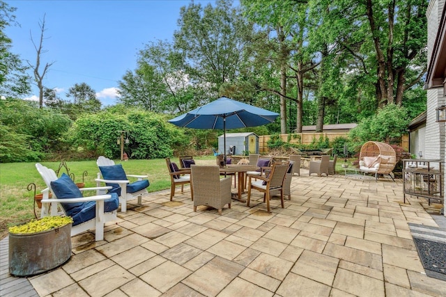 1366 Kirby Rd, Memphis, TN 38120 - view of patio with outdoor dining area, a storage unit, and an outbuilding