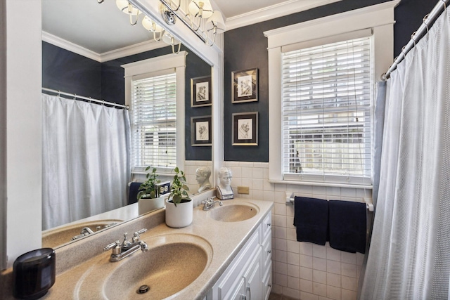 bathroom featuring tile walls, ornamental molding, double vanity, a wainscoted wall, and a shower with curtain