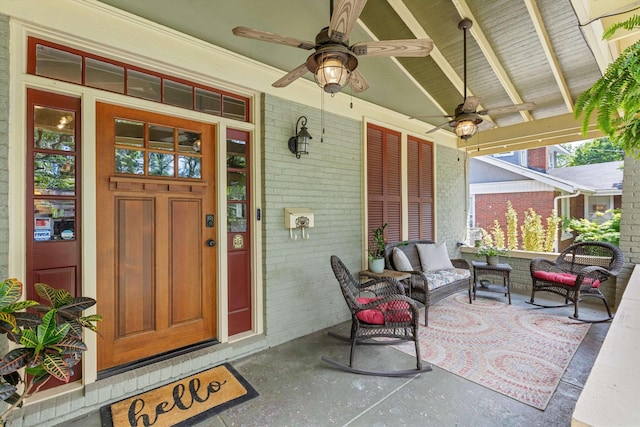 doorway to property with brick siding, ceiling fan, a porch, and an outdoor living space