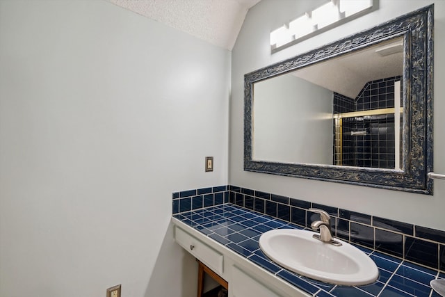 8792 E Carrollwood Ln E, Memphis, TN 38016 - bathroom featuring lofted ceiling, a stall shower, a textured ceiling, vanity, and decorative backsplash