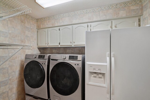 8792 E Carrollwood Ln E, Memphis, TN 38016 - clothes washing area featuring washer and clothes dryer, cabinet space, and a textured ceiling
