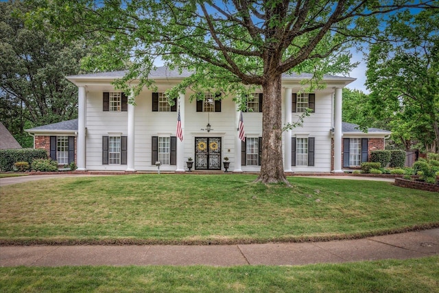 greek revival inspired property with a front lawn, a porch, and roof with shingles