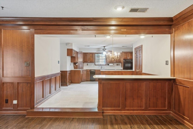 kitchen featuring black appliances, a peninsula, brown cabinetry, light countertops, and a ceiling fan