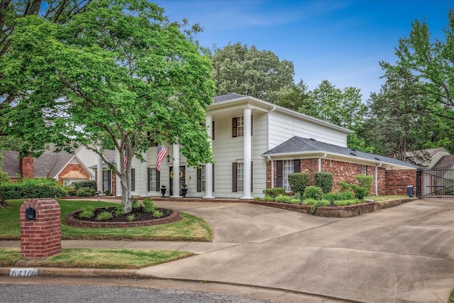 greek revival inspired property featuring curved driveway and brick siding