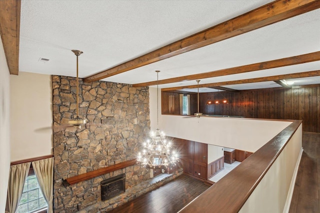 stairs with wood finished floors, wooden walls, beamed ceiling, and a textured ceiling