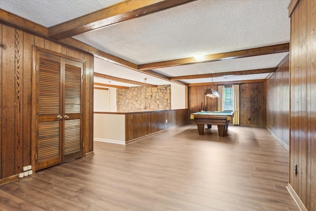 recreation room with wood walls, a textured ceiling, beamed ceiling, wood finished floors, and billiards