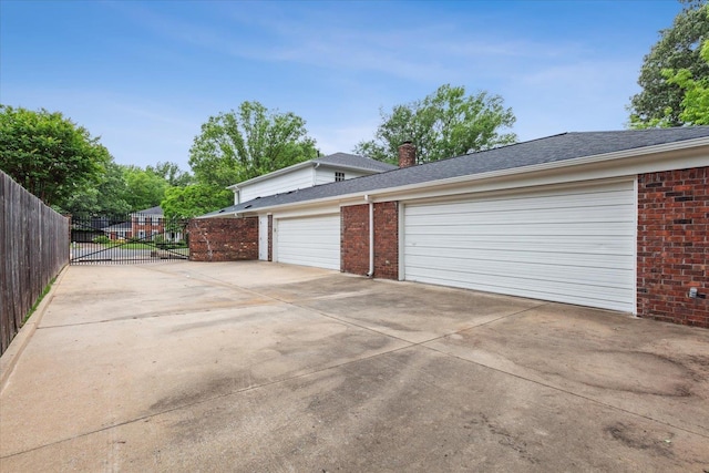 garage featuring driveway, fence, and a gate