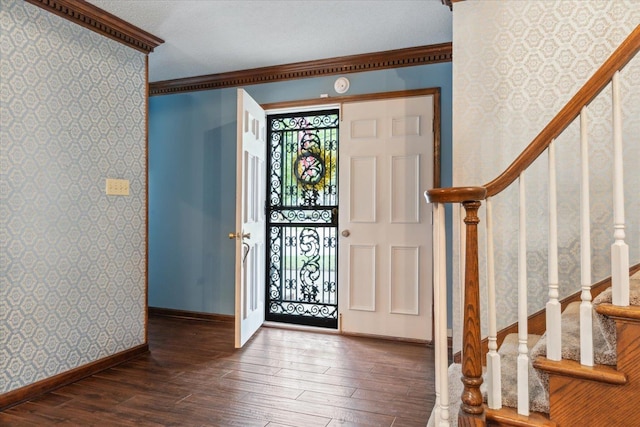 foyer entrance featuring wallpapered walls, hardwood / wood-style flooring, stairs, baseboards, and ornamental molding