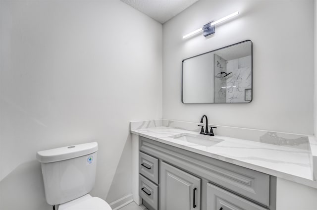 bathroom featuring toilet, vanity, baseboards, and a shower