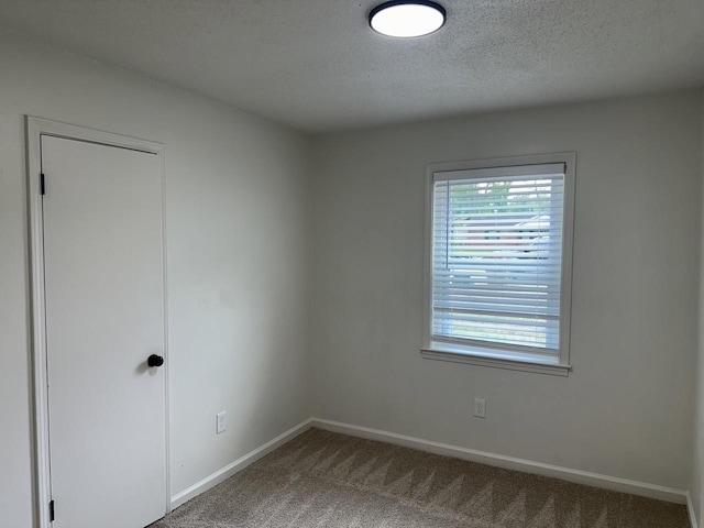 unfurnished room with carpet flooring, baseboards, and a textured ceiling