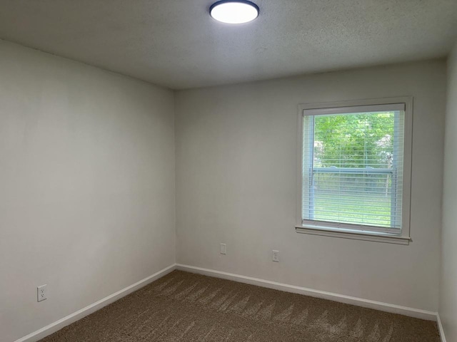 empty room featuring dark carpet and baseboards