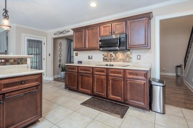 kitchen featuring stainless steel microwave, light countertops, backsplash, ornamental molding, and black electric cooktop