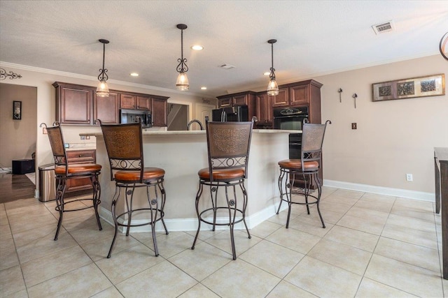 kitchen featuring fridge, oven, stainless steel microwave, a breakfast bar area, and crown molding