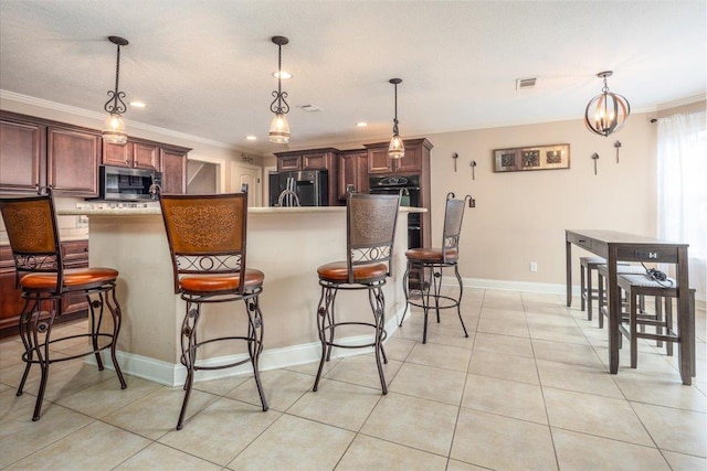 kitchen featuring stainless steel microwave, ornamental molding, fridge, a breakfast bar, and light tile patterned floors