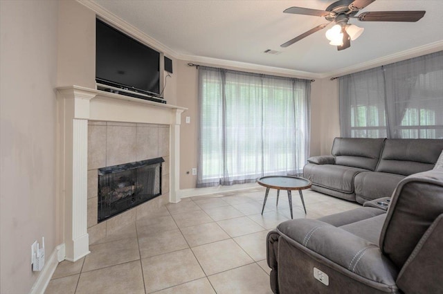 tiled living room with ceiling fan, ornamental molding, baseboards, a tile fireplace, and plenty of natural light