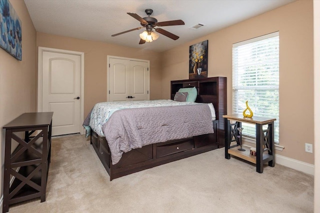 bedroom with light carpet, baseboards, a ceiling fan, and a closet