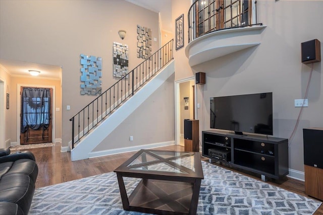 living room with wood finished floors, ornamental molding, stairs, baseboards, and a high ceiling