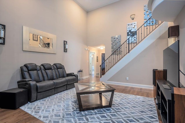 living room with wood finished floors, stairs, baseboards, and a high ceiling