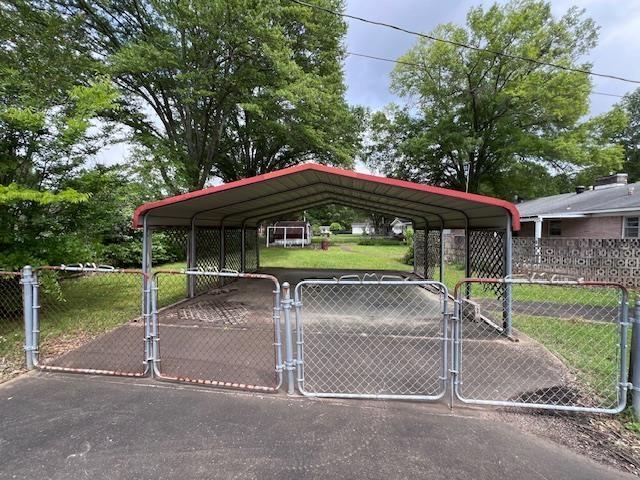 view of parking / parking lot featuring a gate and a carport