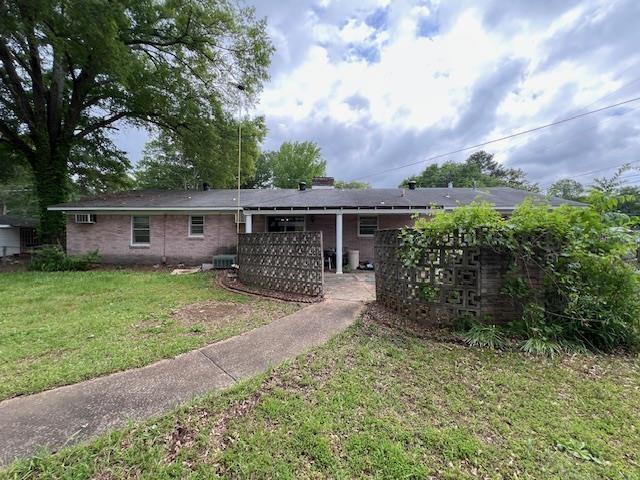 rear view of house featuring a yard, cooling unit, and brick siding
