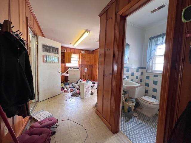 bathroom with tile patterned floors, toilet, wainscoting, and wood walls